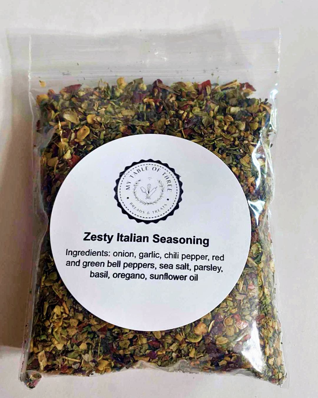 A clear little bag filled with seasoning with a round title label on the front.