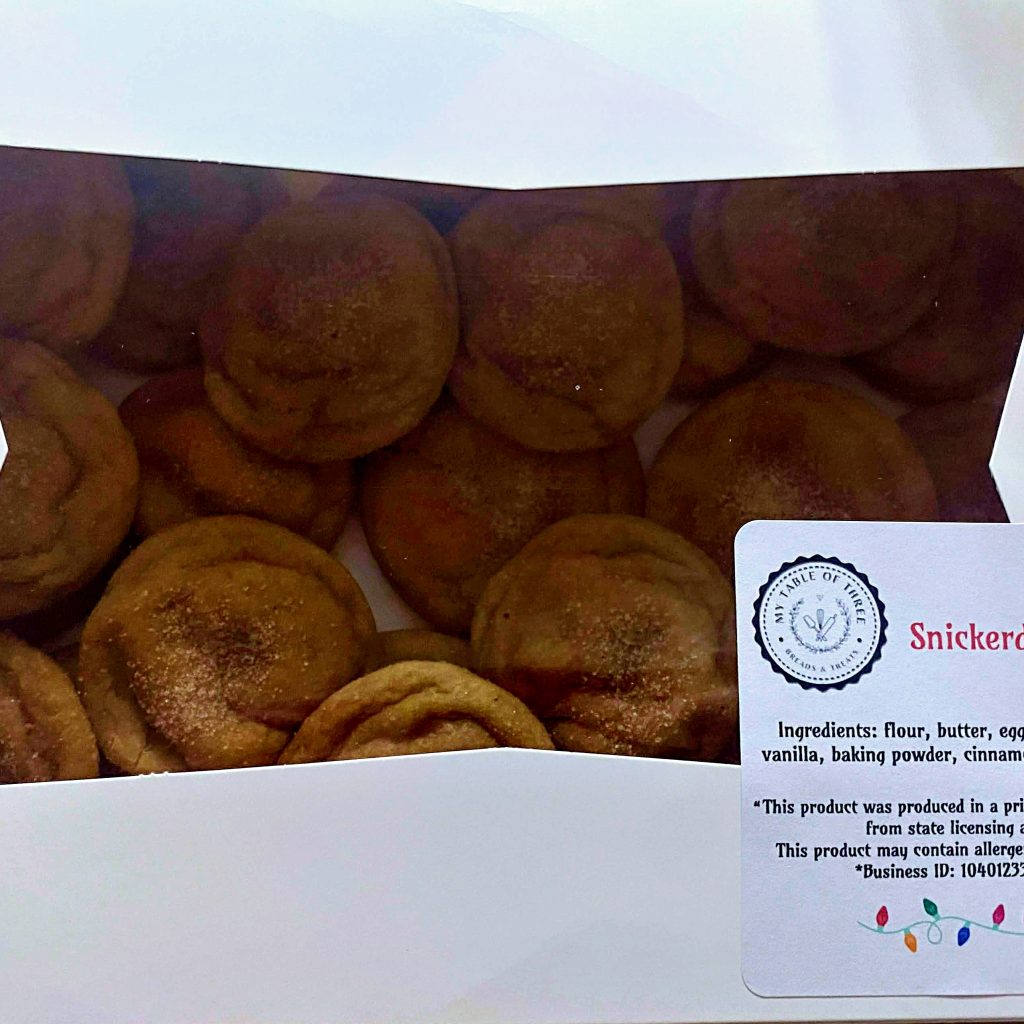 Two dozen snickerdoodle cookies in a white baker box with a label. 