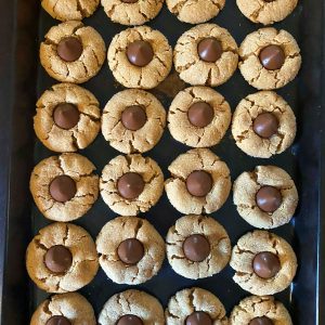 Two dozen Peanut Butter Blossoms lined up on a baking tray.