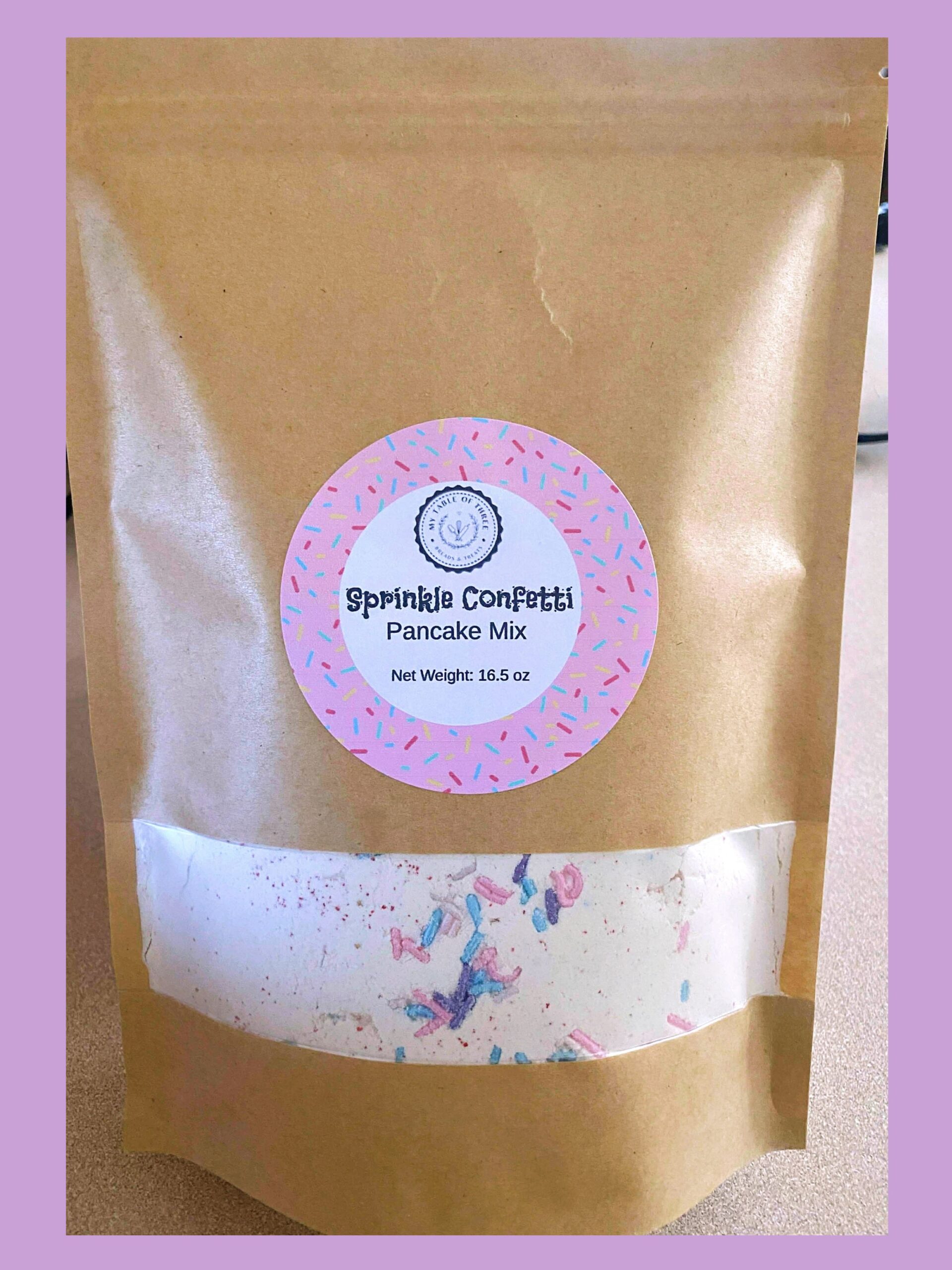 A brown bag of Sprinkle Confetti Pancake Mix from My Table of Three Bakery