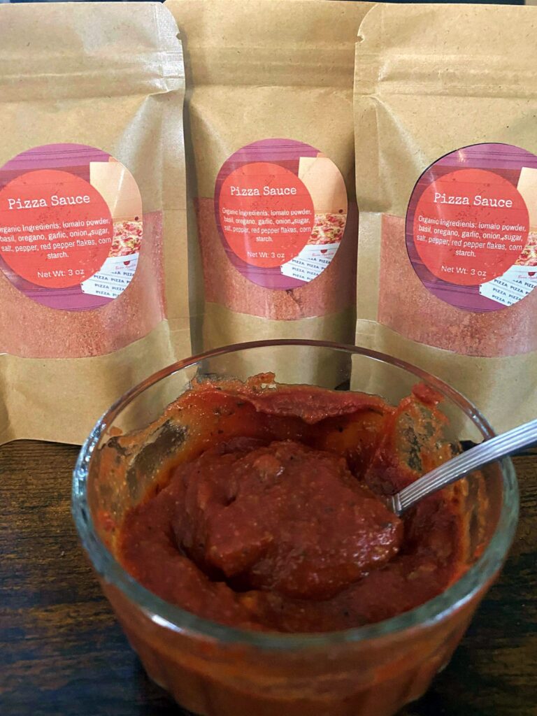 Pizza Sauce Mix Packets with a bowl of made pizza sauce.